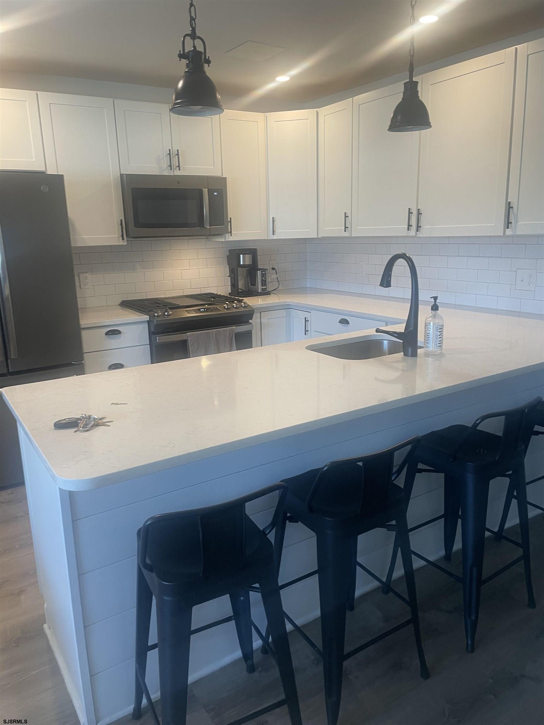 a kitchen with stainless steel appliances a white table chairs and a refrigerator