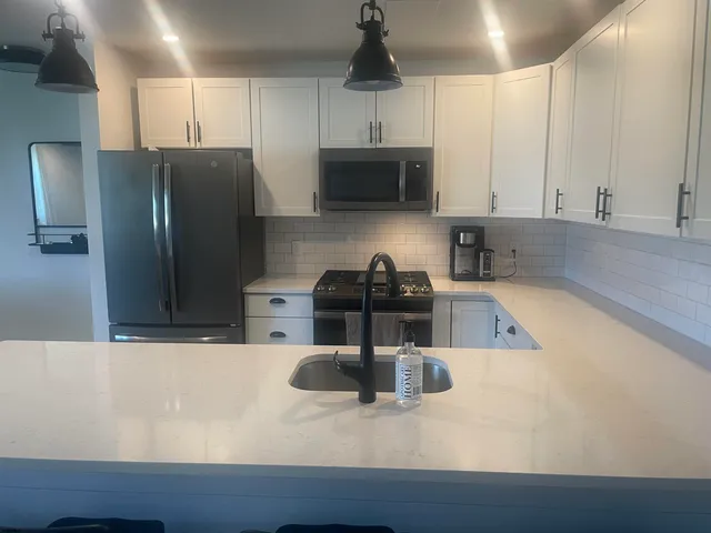 a kitchen with stainless steel appliances granite countertop a sink a stove and a refrigerator