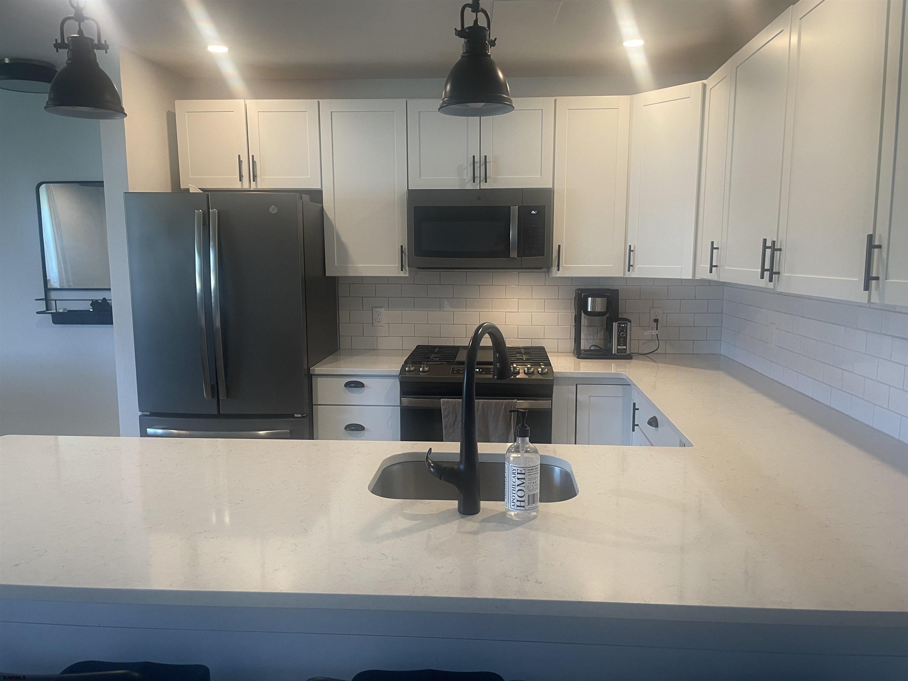 4901 Harbor Beach Boulevard, Unit T12 Brigantine, NJ 08203 - Photo 2 of 8 a kitchen with stainless steel appliances granite countertop a sink a stove and a refrigerator