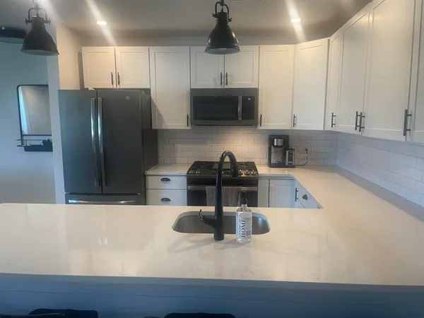 a kitchen with stainless steel appliances granite countertop a sink a stove and a refrigerator