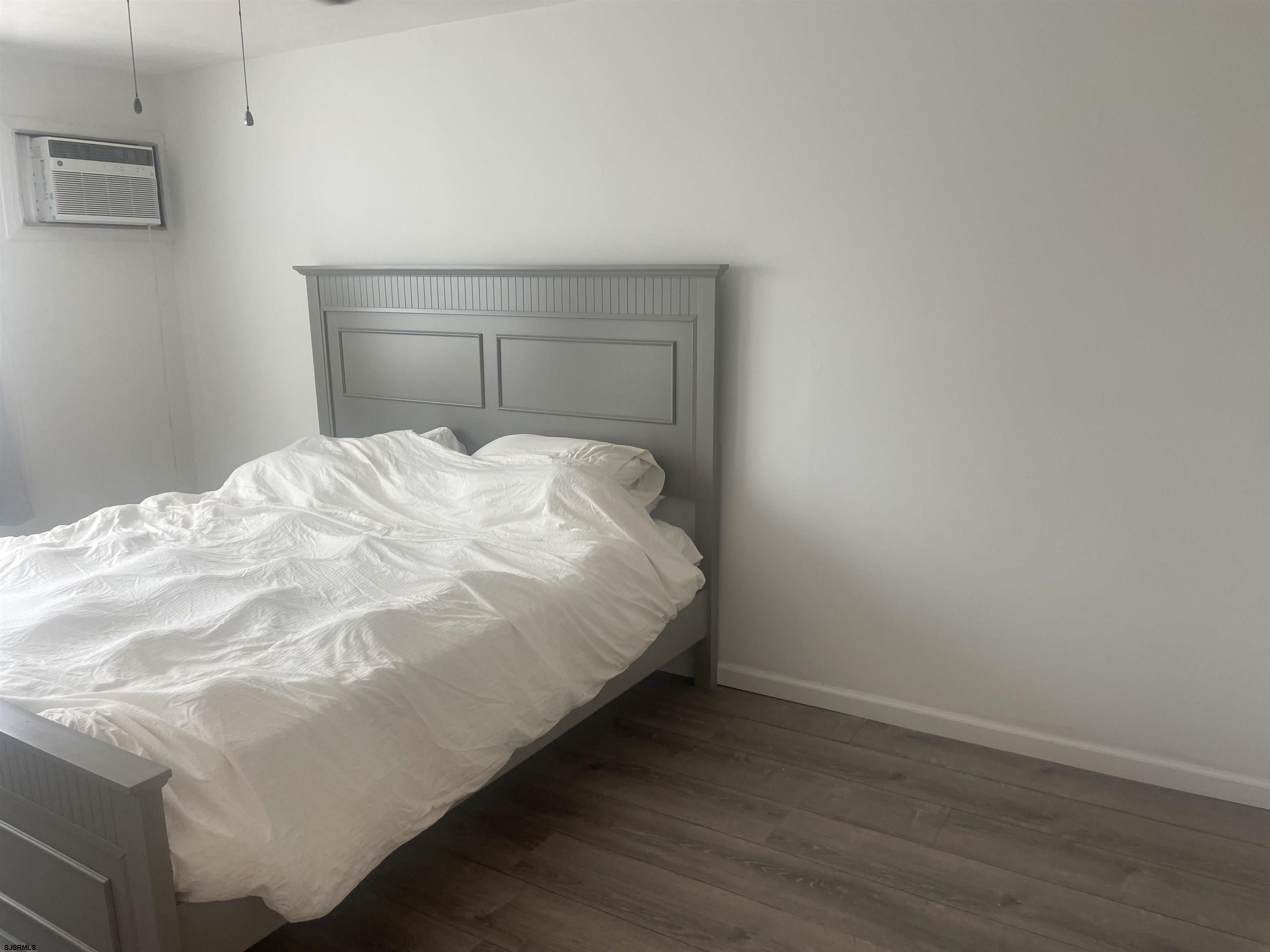 4901 Harbor Beach Boulevard, Unit T12 Brigantine, NJ 08203 - Photo 5 of 8 a bed sitting in a bedroom next to a wooden cabinet