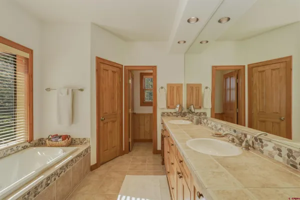 a bathroom with a tub sink double vanity granite tub shower and mirror