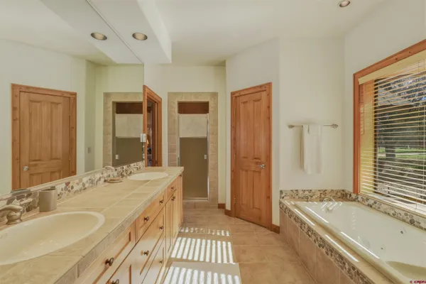 a spacious bathroom with a tub sink and mirror