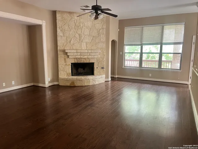 an empty room with wooden floor fireplace and windows