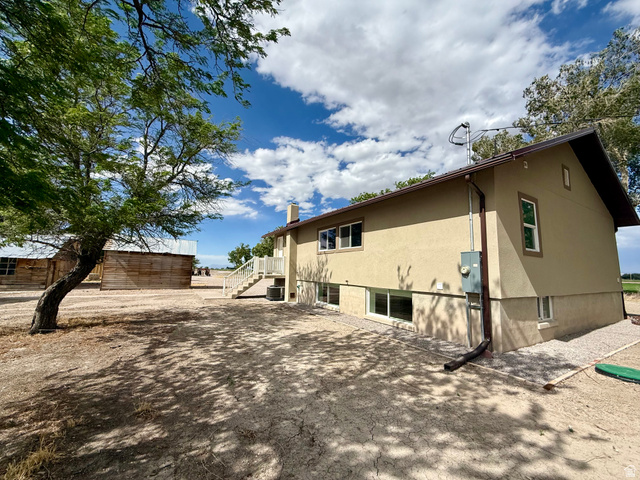 2865 North 3250 W Road Sutherland, UT 84624 - Photo 3 of 28 Two-story stucco residence with a white railing staircase and multiple ground-level windows