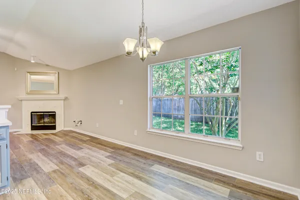 a view of a livingroom with a fireplace large windows and a chandelier
