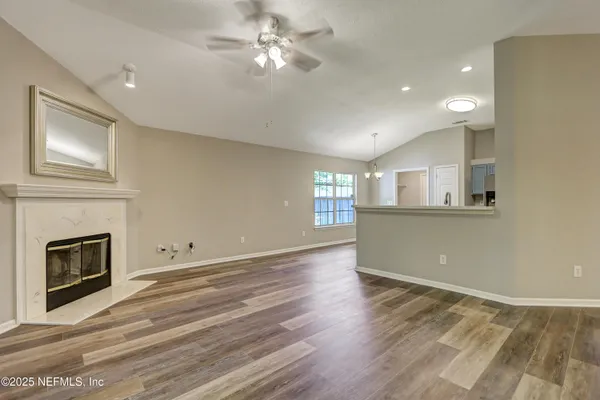 a view of empty room with wooden floor and fan