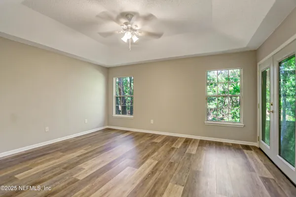 a view of an empty room with a window and wooden floor
