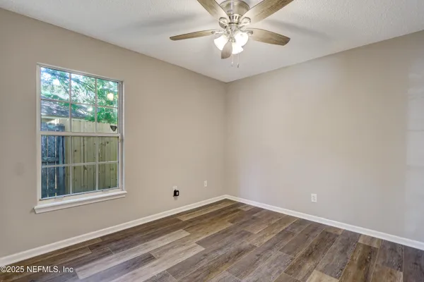 a view of empty room with wooden floor and fan