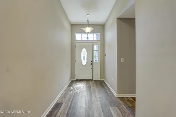 a view of a hallway with wooden floor and a chandelier