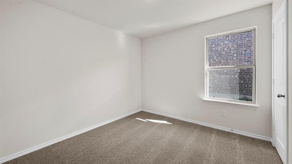 1663 Blaire Drive Tyler, TX 75704 - Photo 24 of 26 Neutral wall paint, gray carpeting, a double-hung window with white trim, and a white interior door with a black doorknob