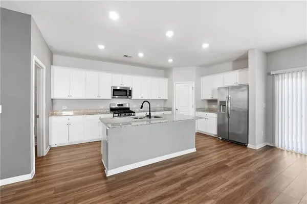 a large kitchen with stainless steel appliances granite countertop a lot of counter space and wooden floors