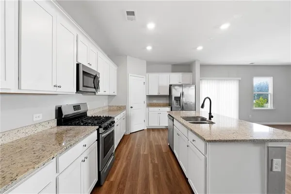 a large kitchen with stainless steel appliances granite countertop a lot of counter space and wooden floors