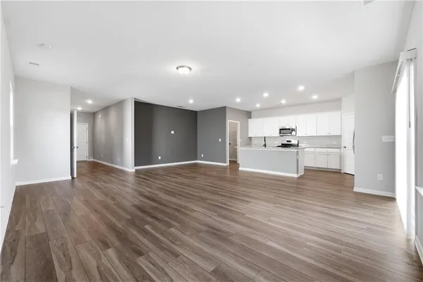 a view of an empty room with wooden floor and windows
