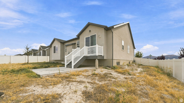 6017 North Sheps Road, Unit C211 Eagle Mountain, UT 84005 - Photo 22 of 25 Exterior featuring light-toned stucco siding, white vinyl fencing, and a concrete patio