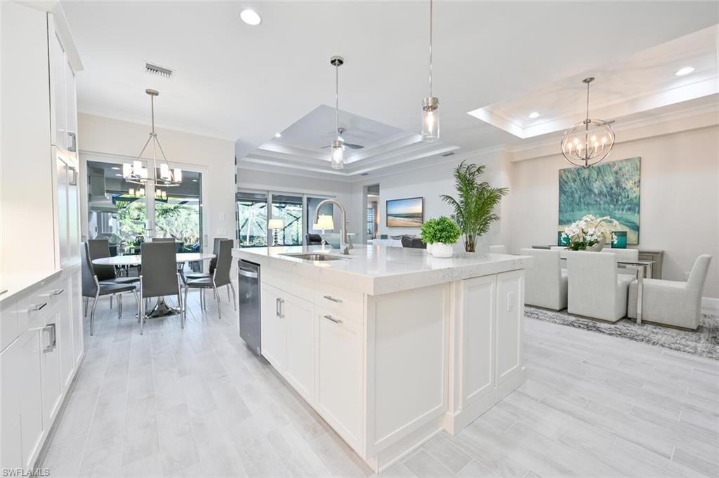 a large white kitchen with lots of counter space and a chandelier