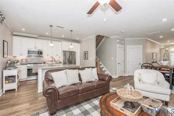 a living room with furniture kitchen view and a wooden floor