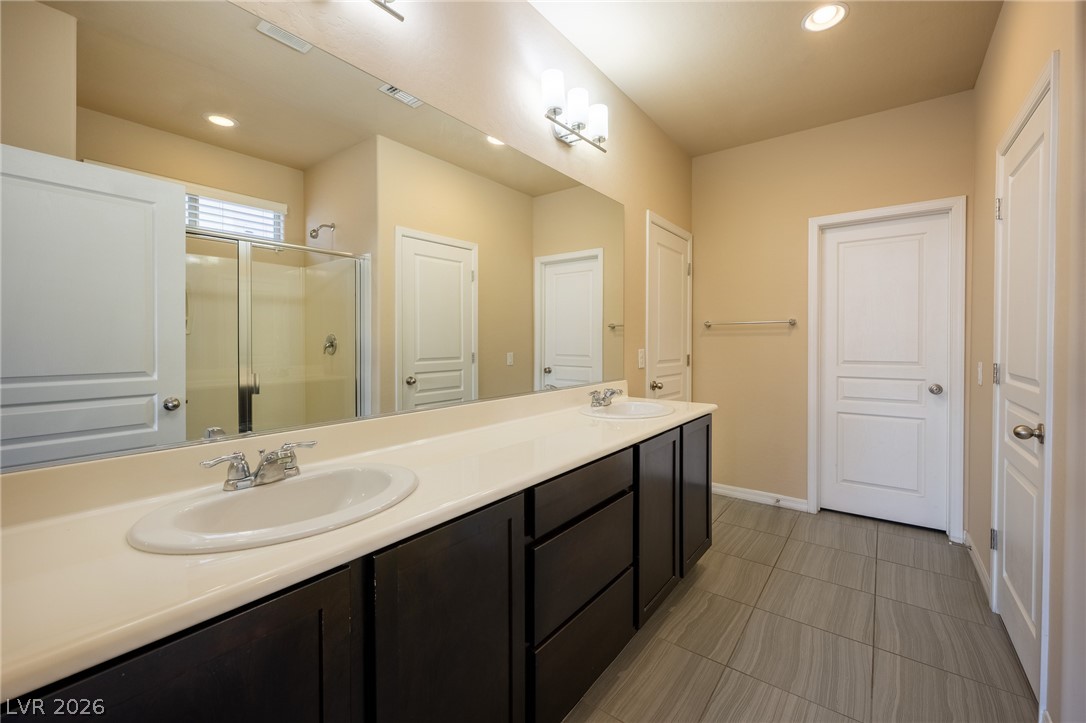 11016 Prairie Grove Road Las Vegas, NV 89179 - Photo 16 of 37 A well-appointed primary bathroom featuring a spacious dual vanity and a convenient glass-enclosed shower.