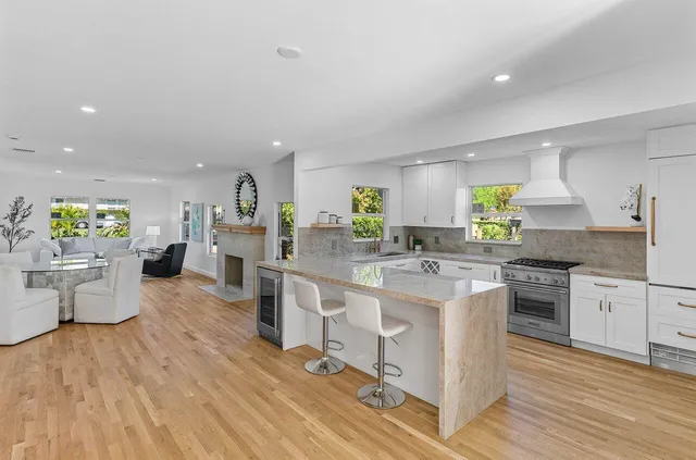a kitchen with stainless steel appliances a white stove top oven a sink dishwasher and a dining table with wooden floor