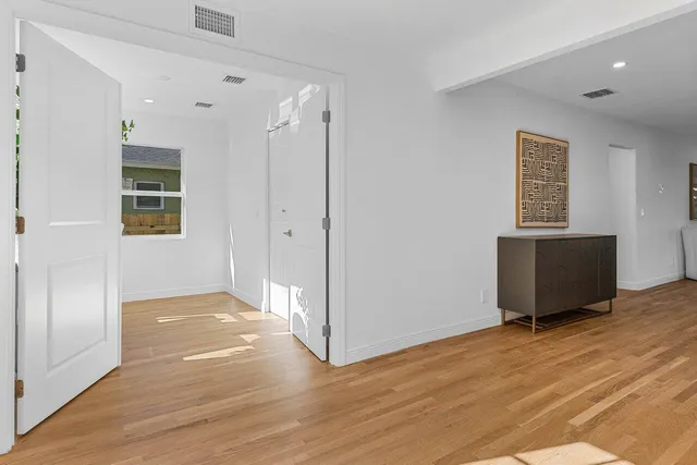 a view of an empty room with wooden floor and a window