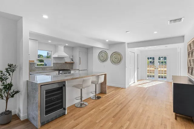 a kitchen with stainless steel appliances granite countertop a stove top oven a sink dishwasher and a refrigerator with wooden floor