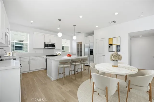 a kitchen with kitchen island stainless steel appliances a dining table chair sink and microwave