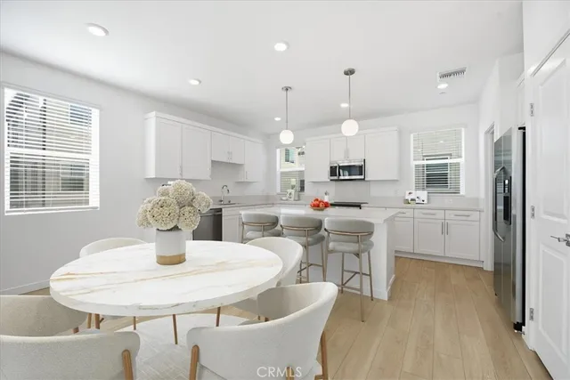 a kitchen with a dining table chairs and refrigerator