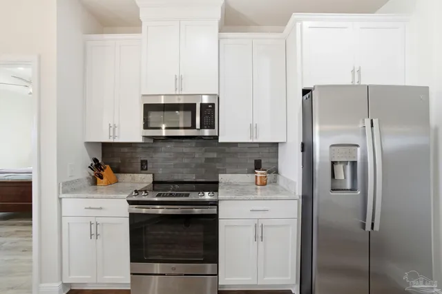 a kitchen with stainless steel appliances a refrigerator a sink a stove and chairs