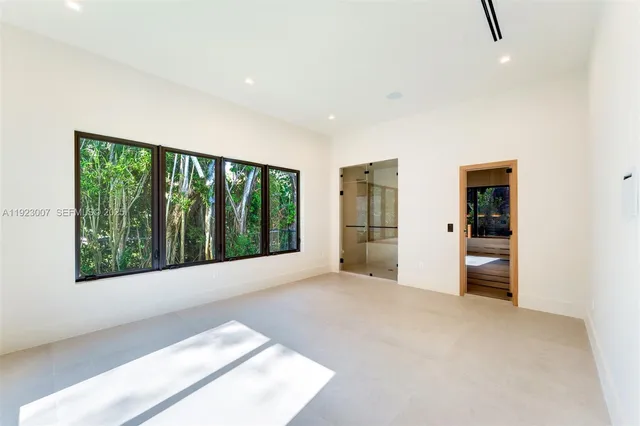 a view of an empty room with a window and a kitchen