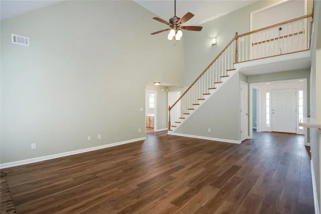 a view of an empty room with wooden floor and a ceiling fan