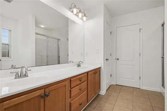 a spacious bathroom with a double vanity sink a large mirror and a shower