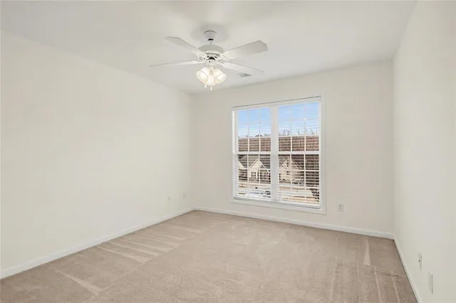 an empty room with chandelier fan and windows