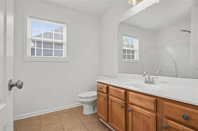 a bathroom with a granite countertop sink a toilet and a window