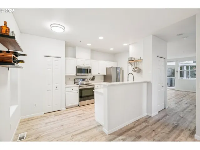 a kitchen with stainless steel appliances kitchen island a sink dishwasher a refrigerator and a stove with wooden floor