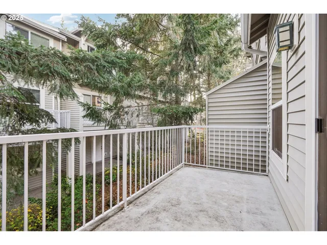 a view of a white house next to a road with a tree
