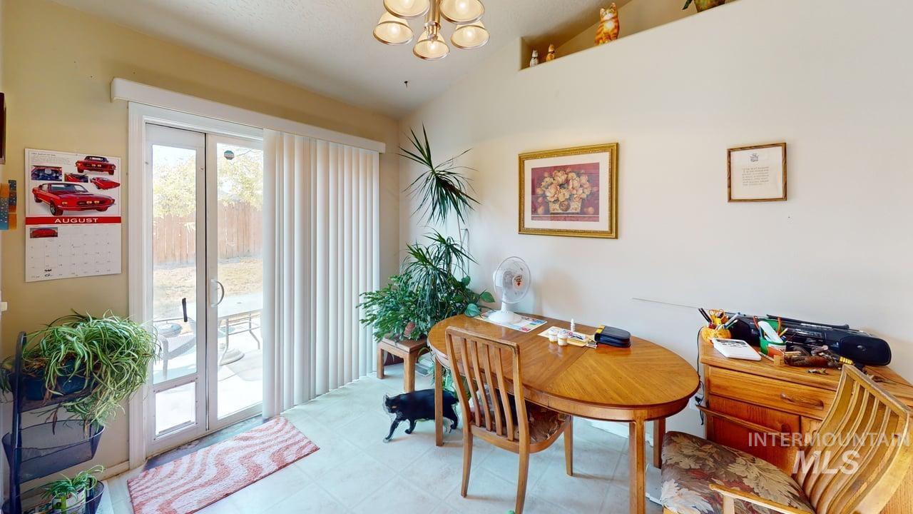 16609 Old Friendship Way Caldwell, ID 83607 - Photo 14 of 23 Vaulted ceiling, contemporary chandelier, sliding glass doors, vertical blinds, and tile flooring
