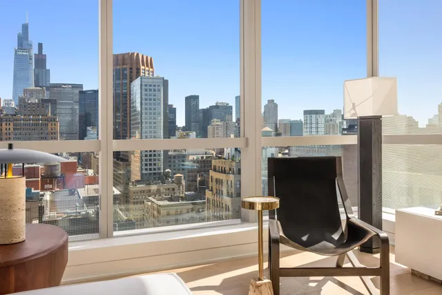 a view of a city from a chair and tables in the balcony