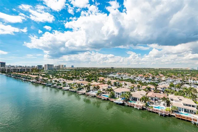 an aerial view of a city with lots of residential buildings ocean and mountain in the back