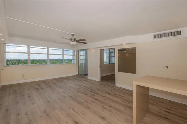 a view of an empty room with wooden floor and a window