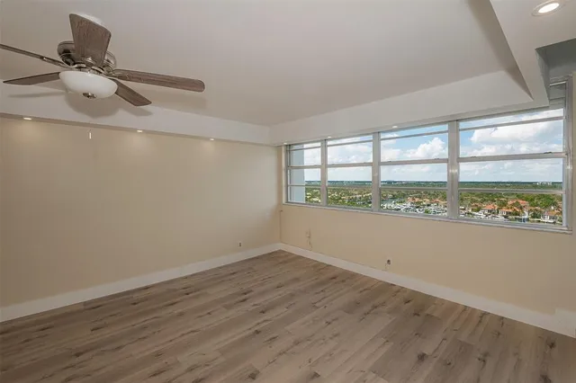 a view of an empty room with wooden floor and a kitchen