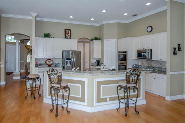 a kitchen with stainless steel appliances granite countertop refrigerator cabinets dining table and chairs