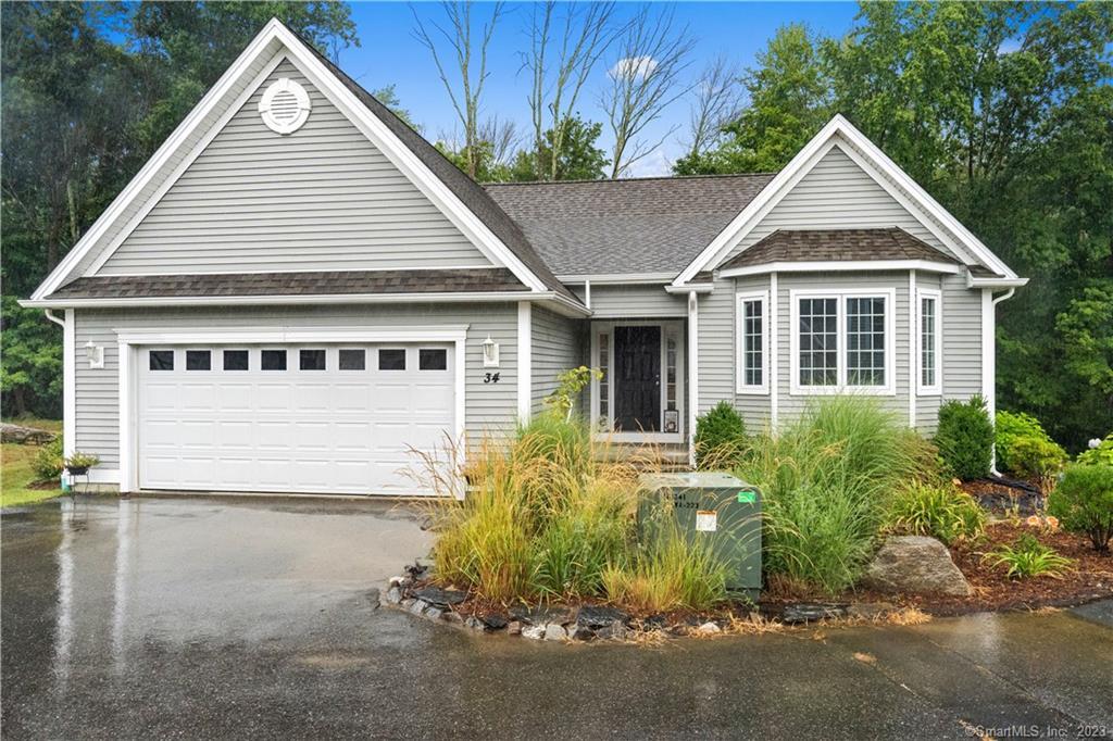 a view of a white house next to a yard with potted plants