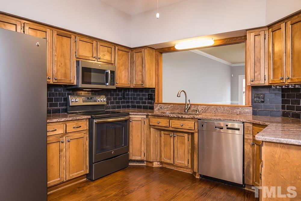 7643 Trowbridge Court Raleigh, NC 27613 - Photo 4 of 26 a kitchen with stainless steel appliances granite countertop a stove a sink and a microwave