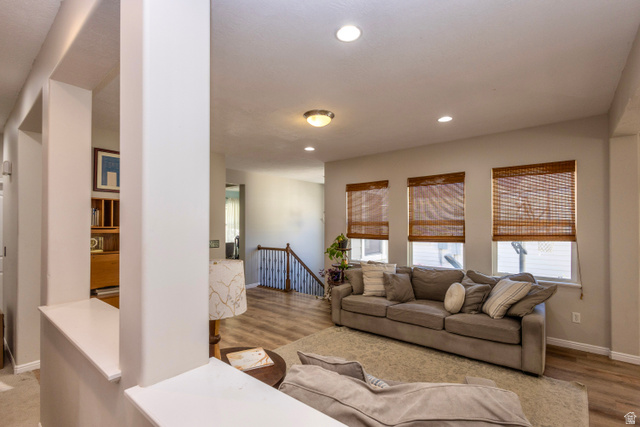 11751 Lake Run Road South Jordan, UT 84009 - Photo 8 of 38 Open-concept living area featuring wood-finish flooring, recessed lighting, and multiple windows with natural fiber blinds