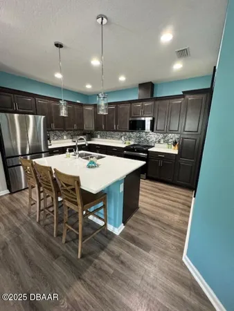 a kitchen with stainless steel appliances granite countertop a stove a refrigerator a oven a sink with a dining table and chairs