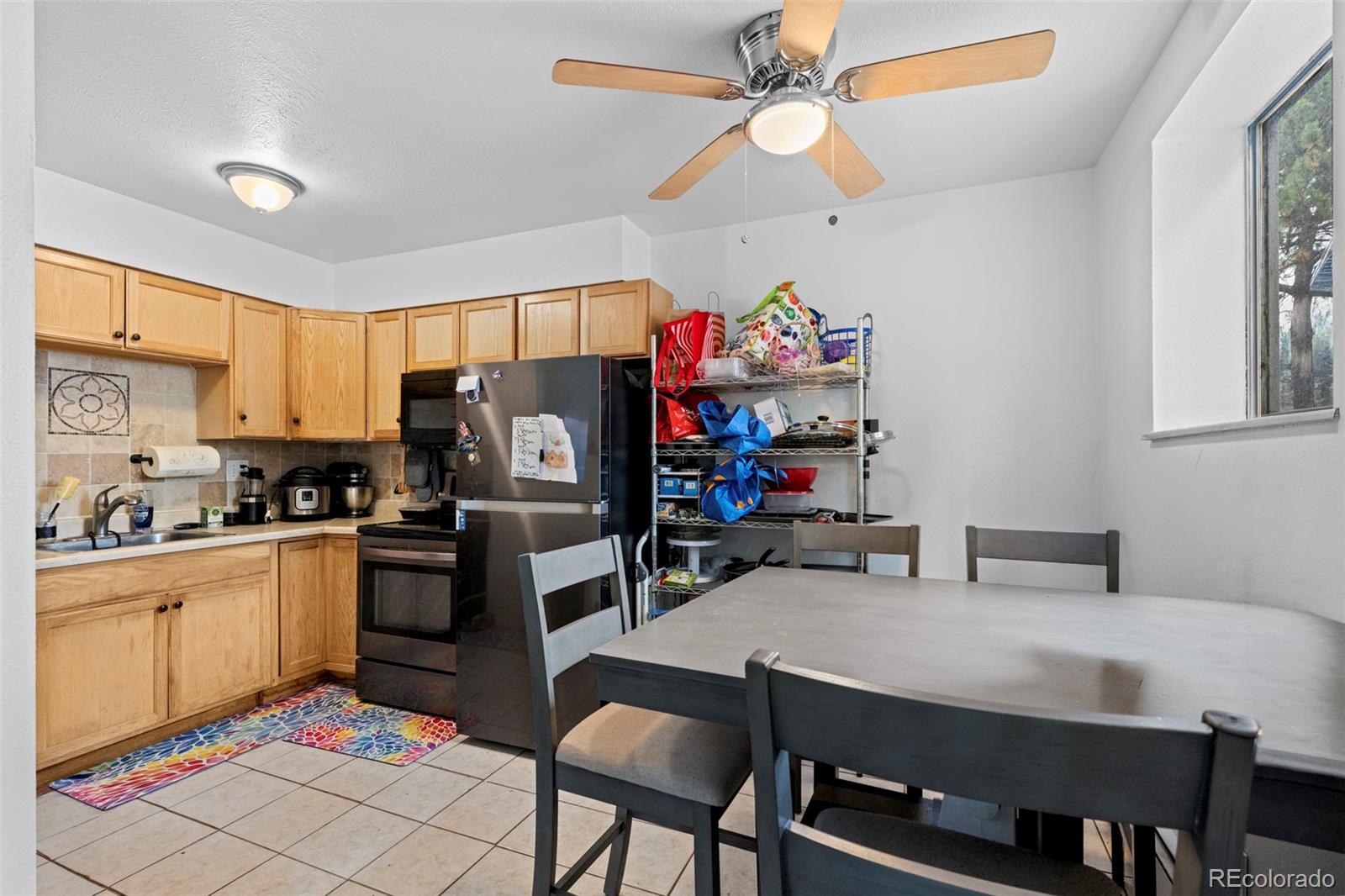 9240 West 49th Avenue, Unit 306 Wheat Ridge, CO 80033 - Photo 2 of 14 a kitchen with a dining table cabinets stainless steel appliances and a window