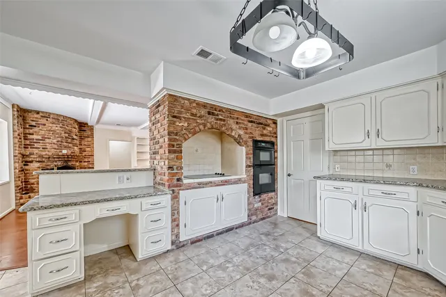 a kitchen with white cabinets and chandelier