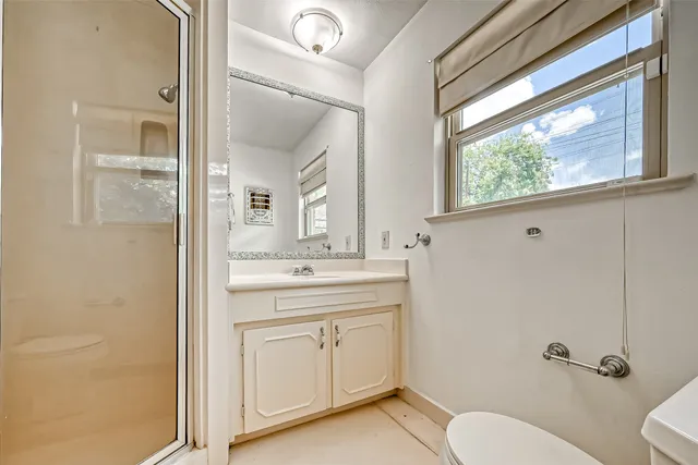 a bathroom with a granite countertop toilet a sink and a mirror