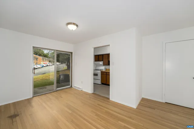 a view of an empty room with a window and kitchen view