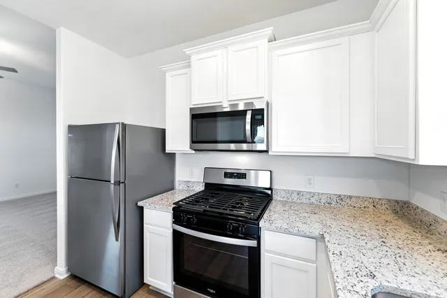 a kitchen with stainless steel appliances granite countertop a stove a refrigerator and a microwave